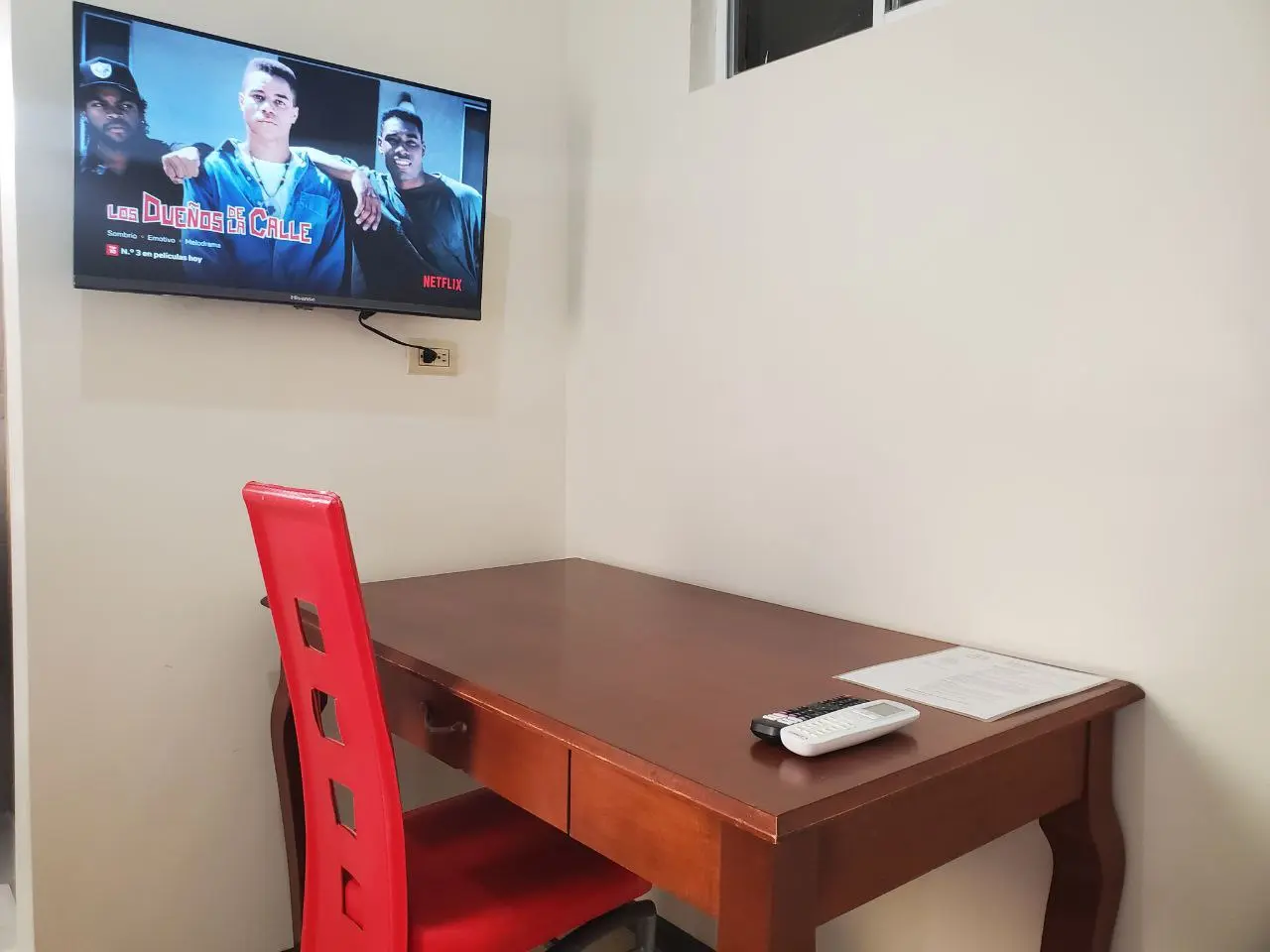 Habitación con cama matrimonial y baño privado en Ciudad Juárez: escritorio de madera, silla y televisión